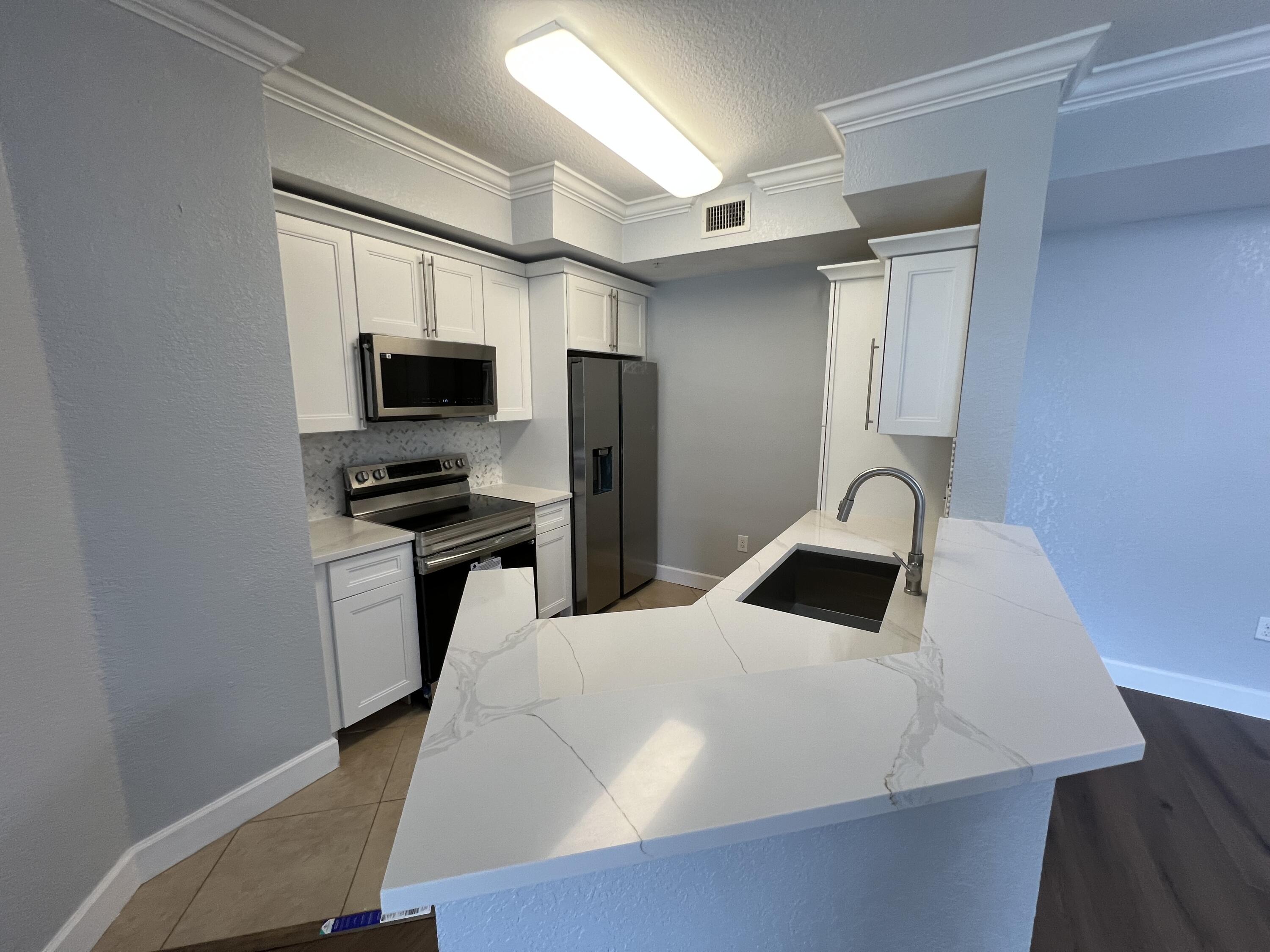 1660 Renaissance Commons Boulevard, Unit 2218 Boynton Beach, FL 33426 - Photo 6 of 23 a kitchen with a refrigerator and a stove top oven