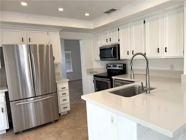 a kitchen with granite countertop white cabinets and stainless steel appliances