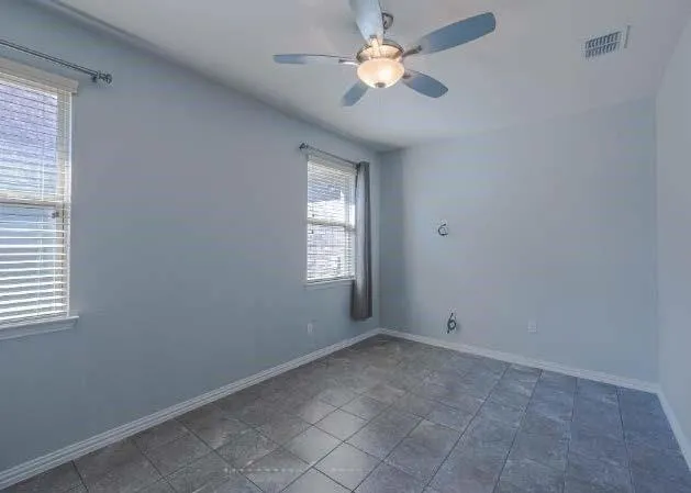 an empty room with windows and fan