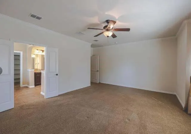 an empty room with chandelier fan and windows