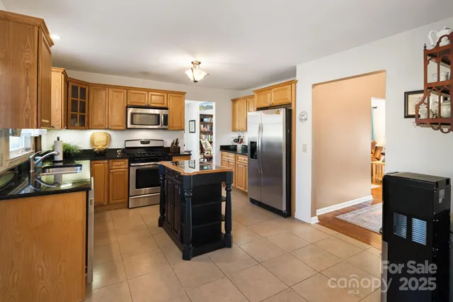 a kitchen with granite countertop a refrigerator a stove top oven and a dining table