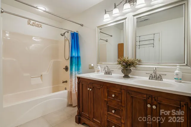 a bathroom with a sink double vanity granite tub shower and a mirror