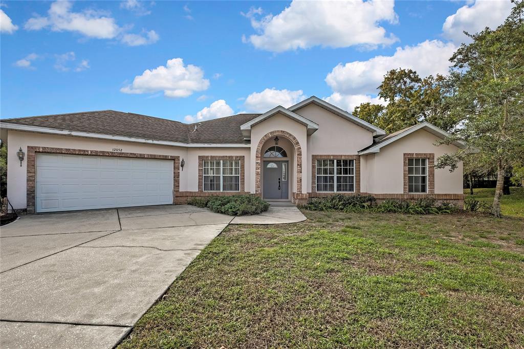 12052 Jade Avenue Spring Hill, FL 34609 - Photo 1 of 45 a front view of a house with a yard and garage
