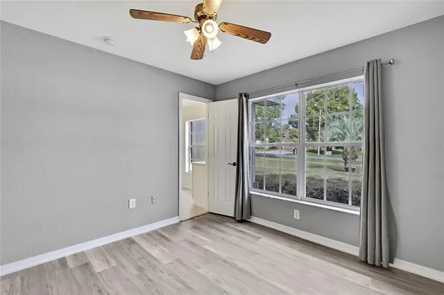 an empty room with wooden floor and ceiling fan