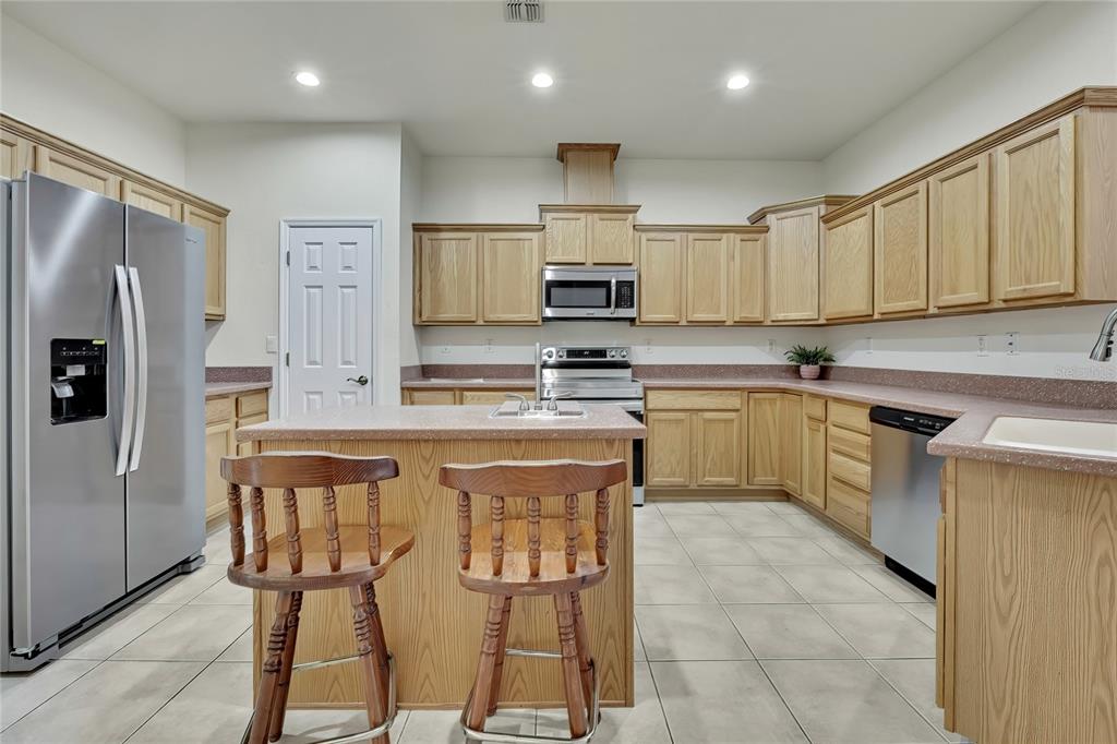 12052 Jade Avenue Spring Hill, FL 34609 - Photo 9 of 45 a kitchen with stainless steel appliances granite countertop a stove a sink a microwave and a refrigerator