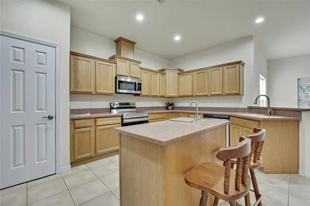 a kitchen with stainless steel appliances granite countertop a sink a stove a refrigerator cabinets and chairs