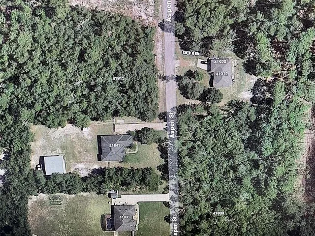 an aerial view of a house with a yard and trees all around