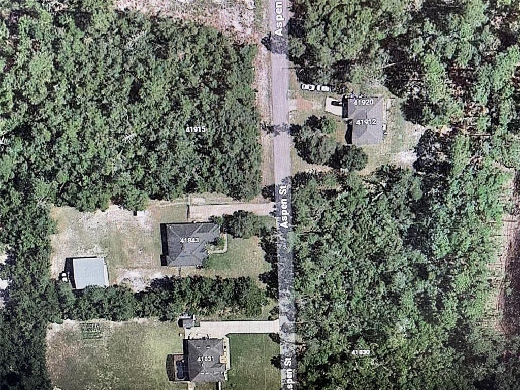 an aerial view of a house with a yard and trees all around