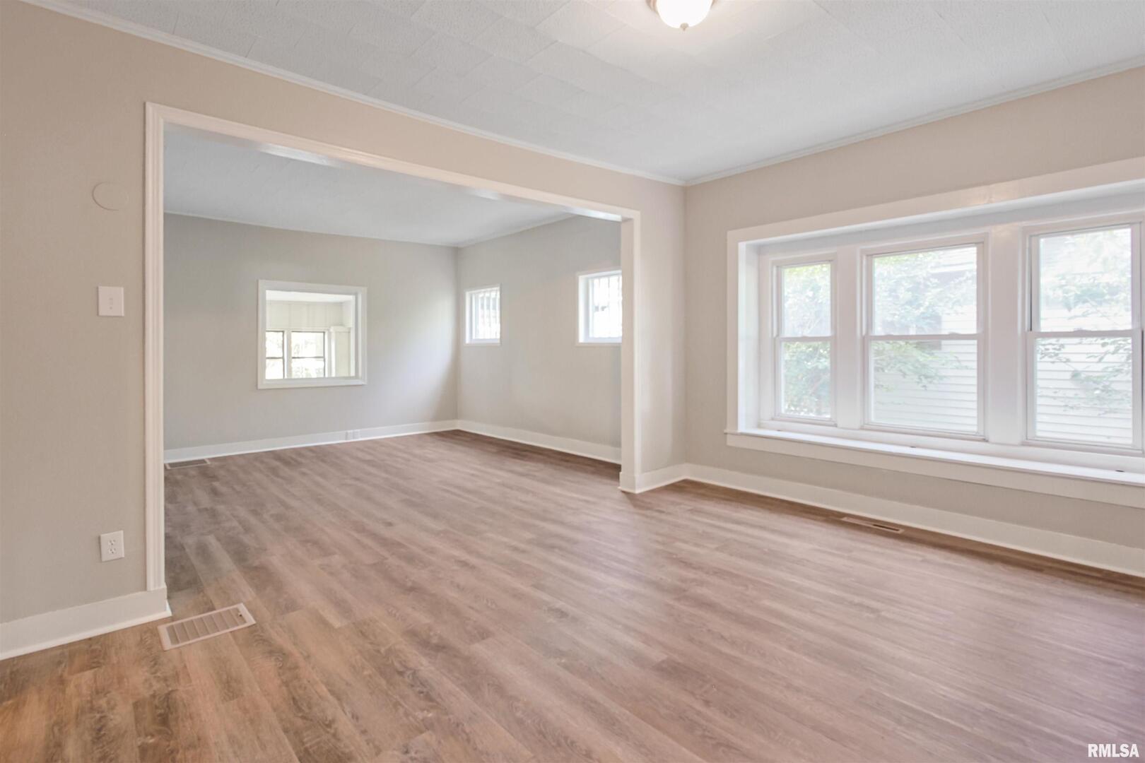208 South 10th Street Herrin, IL 62948 - Photo 4 of 24 an empty room with wooden floor and windows