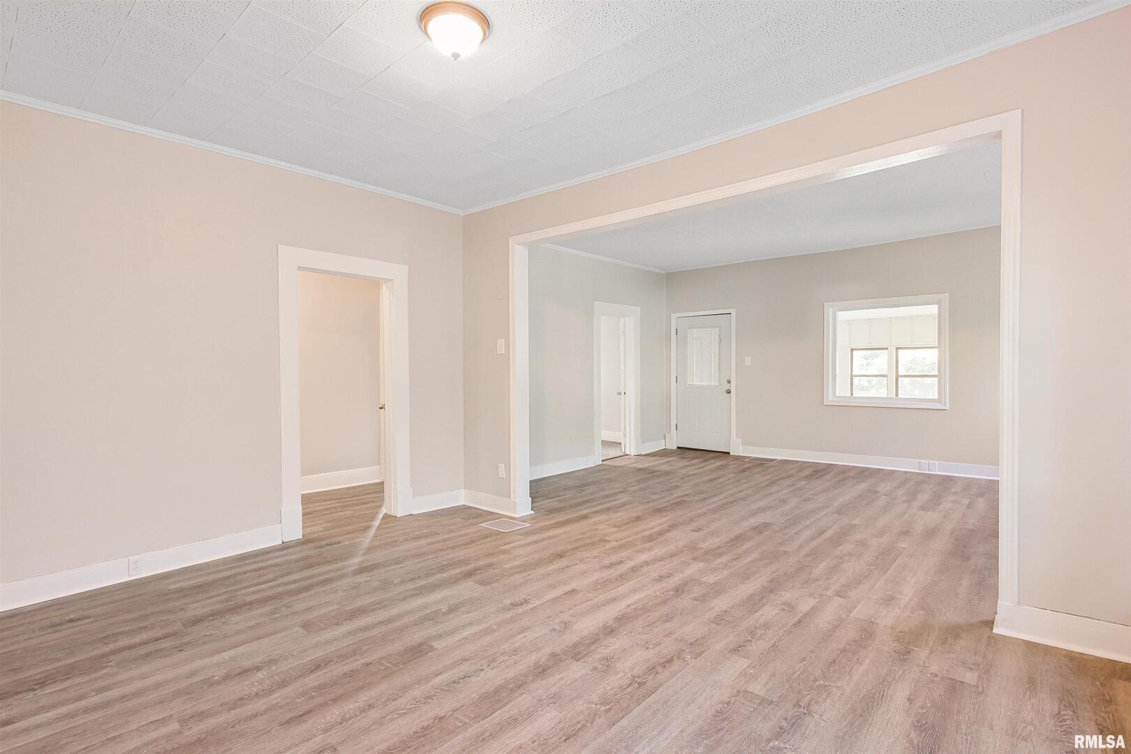 208 South 10th Street Herrin, IL 62948 - Photo 5 of 24 an empty room with wooden floor and windows