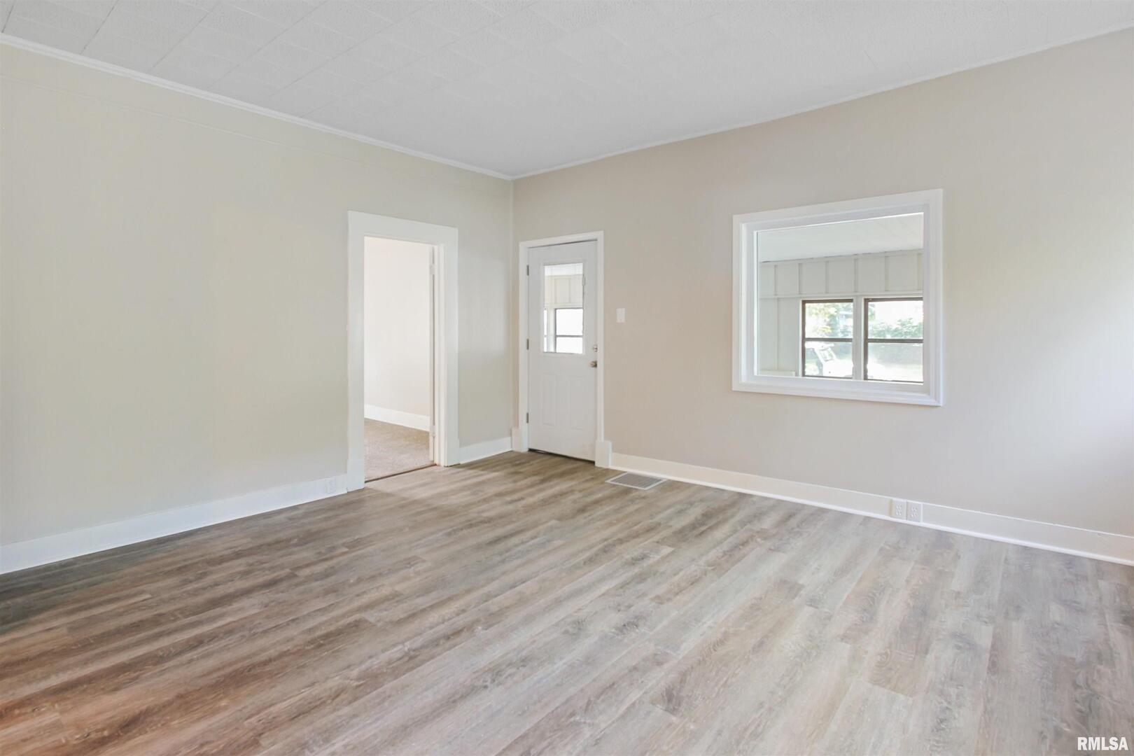 208 South 10th Street Herrin, IL 62948 - Photo 6 of 24 an empty room with wooden floor and windows