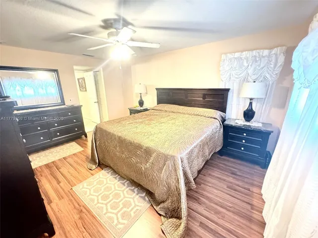 a spacious bedroom with a bed and a flat tv screen on dresser