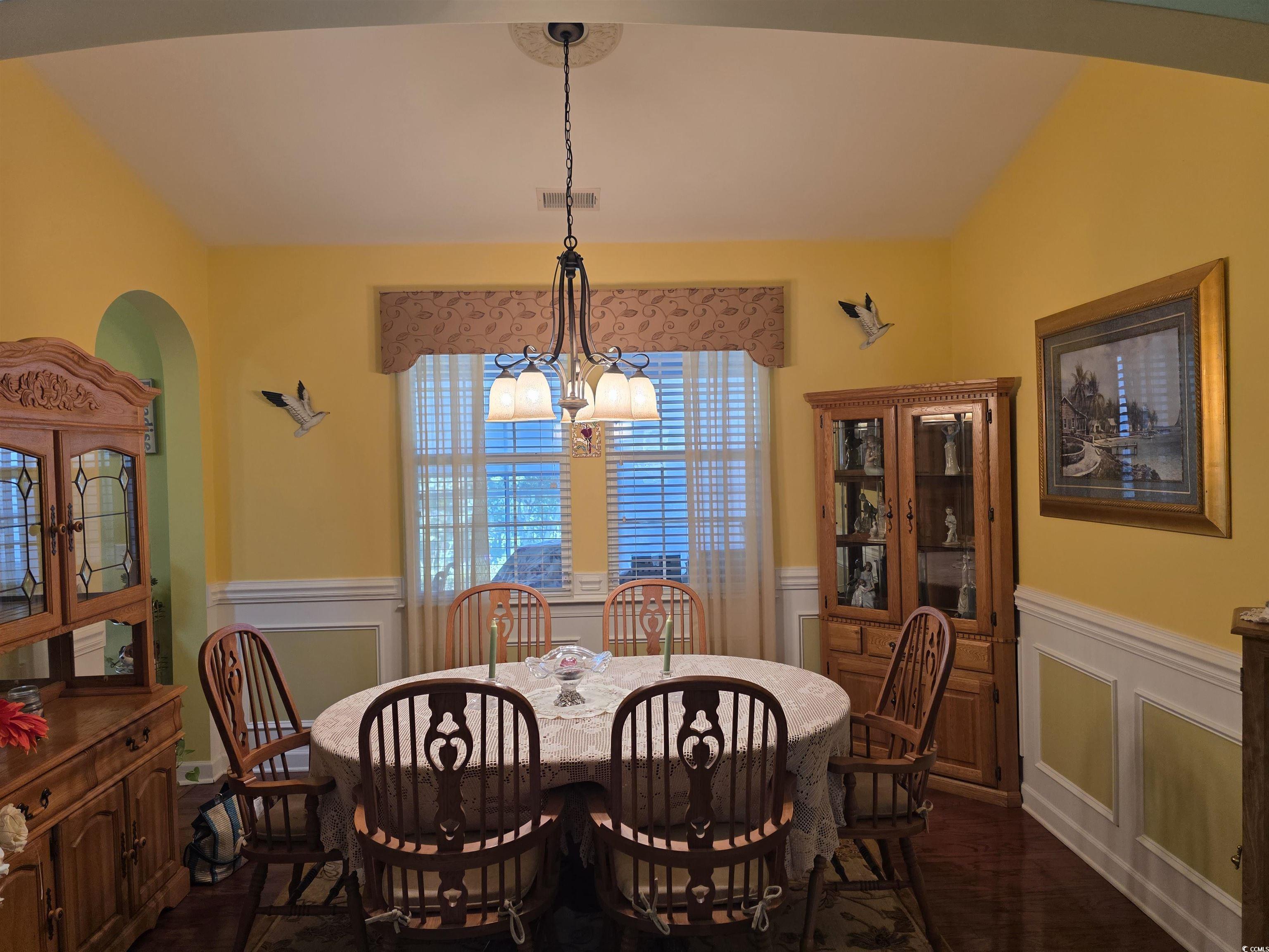 1575 Berkshire Avenue Myrtle Beach, SC 29577 - Photo 14 of 30 Dining room featuring a chandelier, dark wood finished floors, wainscoting, and a decorative wall