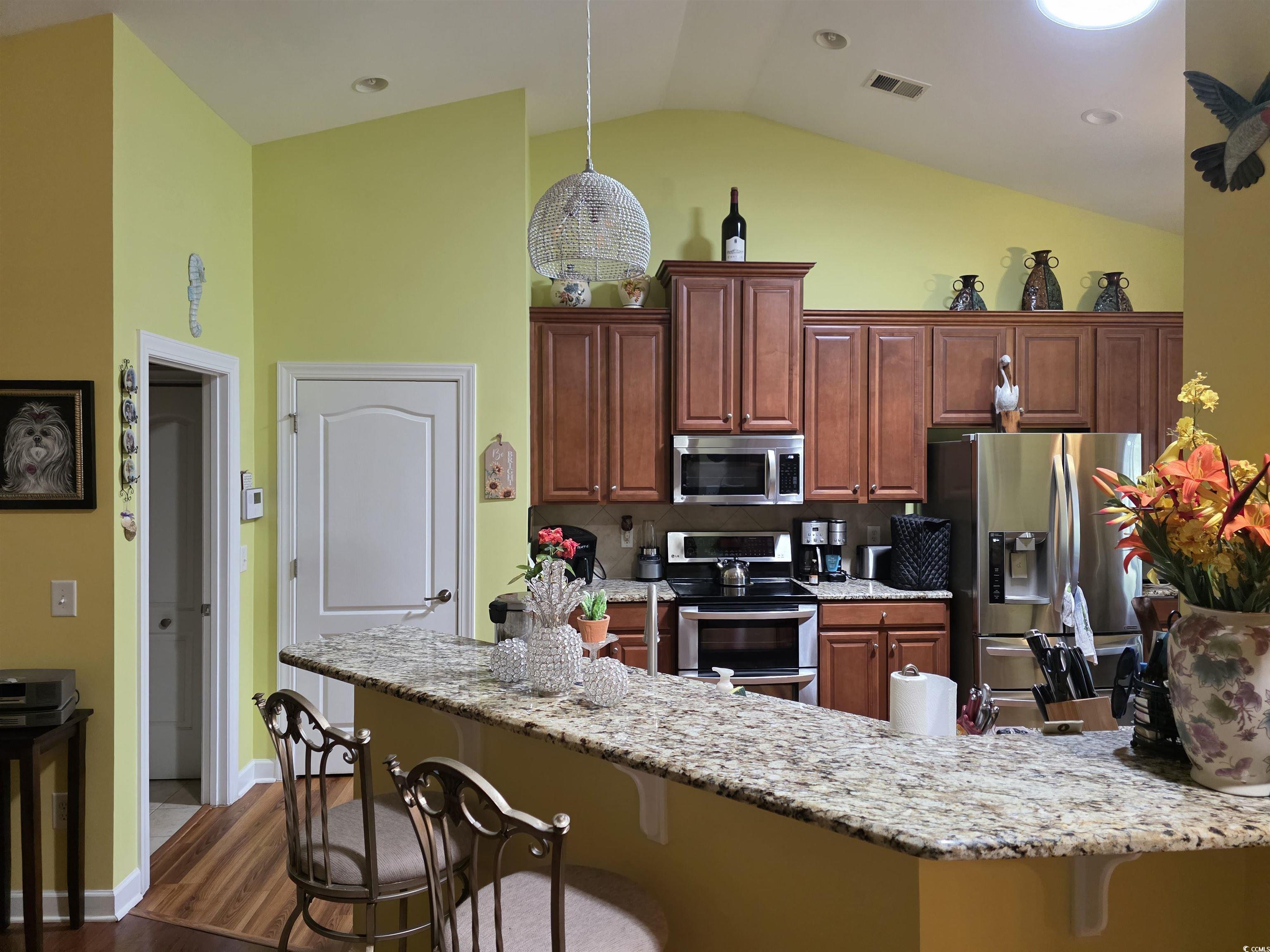 1575 Berkshire Avenue Myrtle Beach, SC 29577 - Photo 15 of 30 Kitchen with a breakfast bar, light stone countertops, stainless steel appliances, dark wood finished floors, and decorative light fixtures