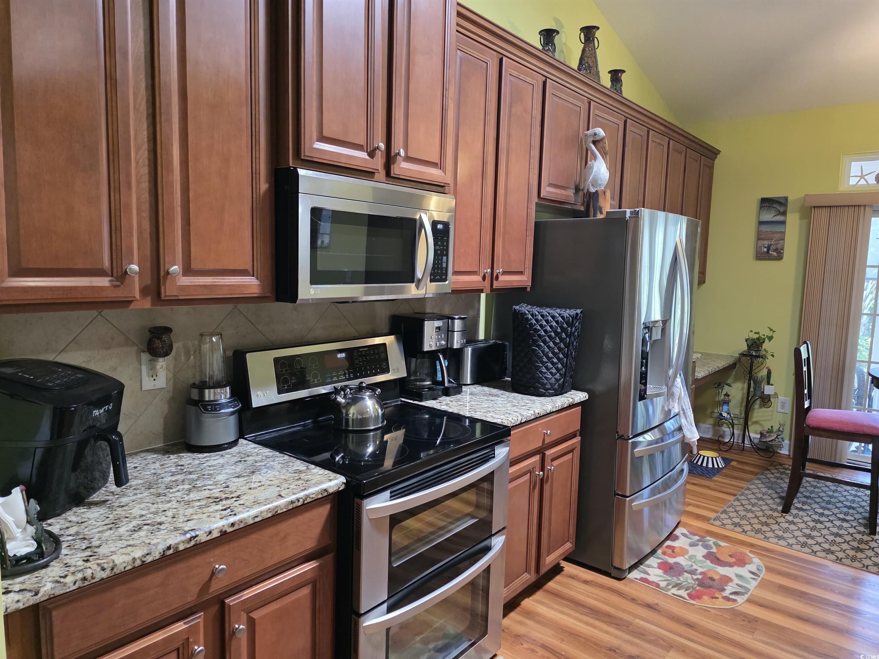 1575 Berkshire Avenue Myrtle Beach, SC 29577 - Photo 23 of 30 Kitchen with appliances with stainless steel finishes, light stone counters, light wood-style floors, backsplash, and vaulted ceiling
