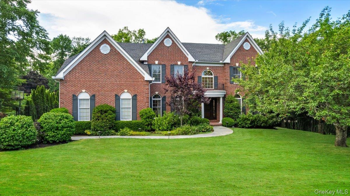 32 Rolling Ridge Road White Plains, NY 10605 - Photo 2 of 32 Brick exterior featuring multiple gables, arched windows with shutters, a covered entry, and a mature landscaped front yard with a curved pathway