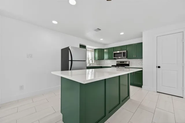 a kitchen with kitchen island a sink stainless steel appliances and cabinets