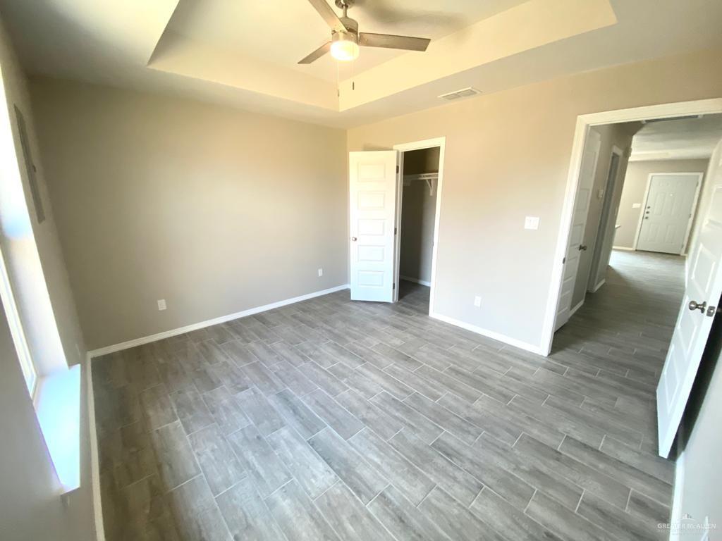 1105 West Kennedy Street, Unit 17 Pharr, TX 78577 - Photo 8 of 11 Unfurnished bedroom with a tray ceiling, wood finish floors, and a ceiling fan