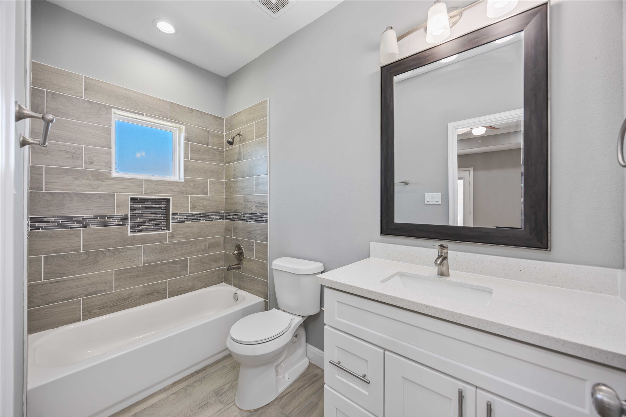 4903 Mallow Street, Unit A Houston, TX 77033 - Photo 9 of 10 This shows a modern, updated bathroom. It has a white vanity area, Bathtub and shower and a toilet in between vanity and bathtub.