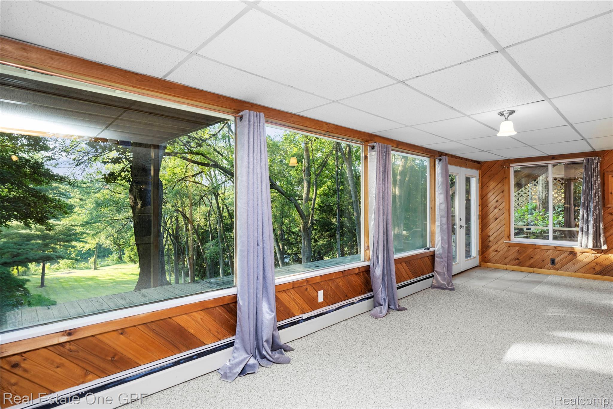 5068 Atkins Road North Street, MI 48049 - Photo 43 of 78 Expansive windows, wood-paneled walls, carpeted flooring, white grid ceiling, and a white ceiling light fixture