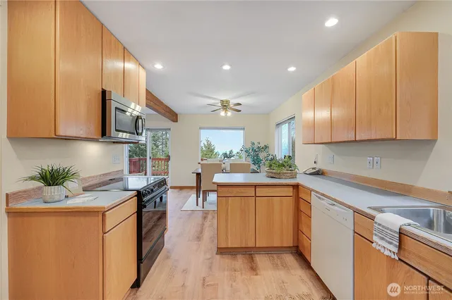 a kitchen with stainless steel appliances granite countertop a sink a stove a refrigerator cabinets and living room view