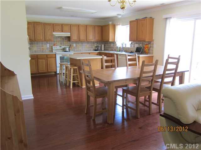 5927 Brightstar Valley Road Mint Hill, NC 28227 - Photo 6 of 14 a kitchen with stainless steel appliances granite countertop a stove a refrigerator a dining table and chairs with wooden floor