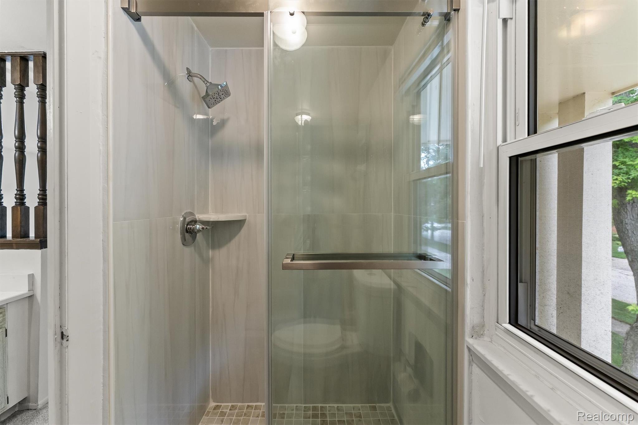 2118 Rutgers Drive Troy, MI 48085 - Photo 26 of 39 Glass-enclosed shower featuring large format tile walls, a built-in shelf, and mosaic tile flooring