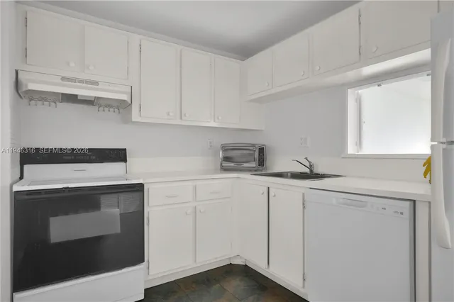 a kitchen with white cabinets and sink