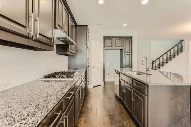 a kitchen with stainless steel appliances granite countertop a stove a sink and a refrigerator