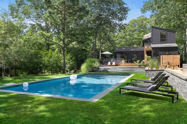 a view of backyard with swimming pool and trees
