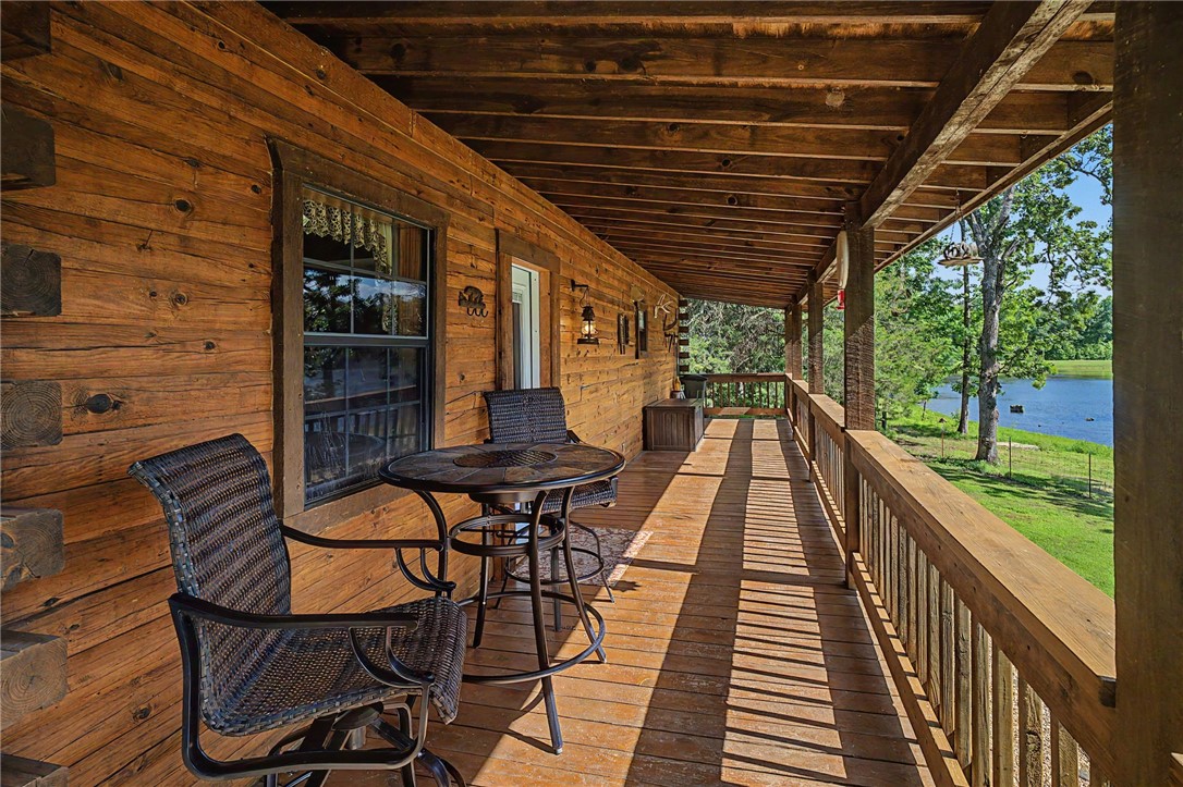 21019 Carter Road West Fork, AR 72774 - Photo 3 of 49 Expansive wooden porch with a natural wood plank floor, log-style exterior walls, and a matching wooden railing