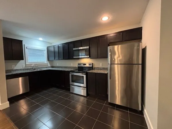 a kitchen with granite countertop stainless steel appliances and refrigerator
