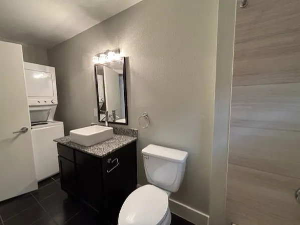 a bathroom with a granite countertop toilet sink and mirror