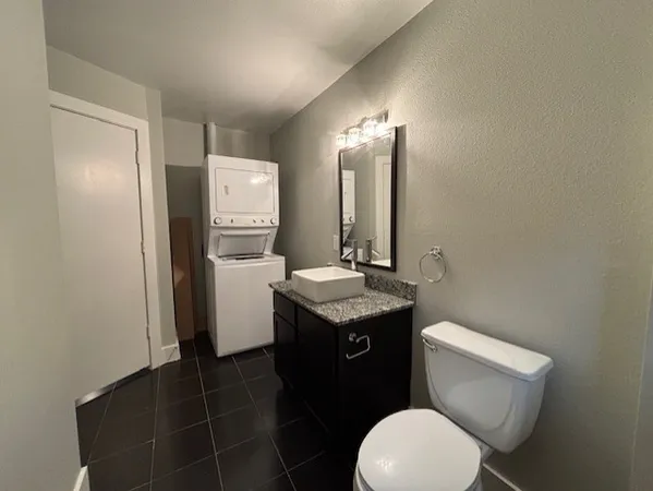 a bathroom with a granite countertop toilet sink and mirror