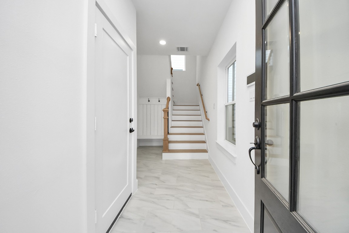 723 Marcella Street, Unit B Houston, TX 77091 - Photo 4 of 22 Enter thru the front door to begreeted by bright, clean entry way with a staircase leading up. The space features modern finishes with a tiled floor, natural light from a window, and a welcoming, neutral color palette.
