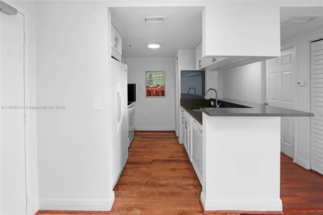 a kitchen with stainless steel appliances a refrigerator sink and white cabinets