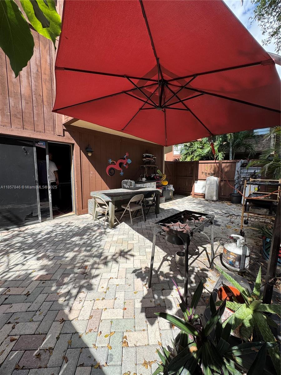6445 Southwest 116th Place, Unit A Miami, FL 33173 - Photo 21 of 25 a view of a patio with table and chairs under an umbrella