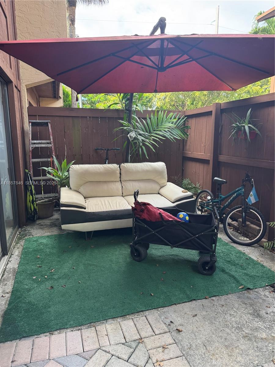 6445 Southwest 116th Place, Unit A Miami, FL 33173 - Photo 3 of 25 a view of a patio with table and chairs under an umbrella