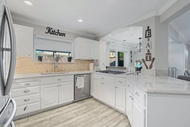 a view of a granite countertop cabinets sink and dishwasher with wooden floor