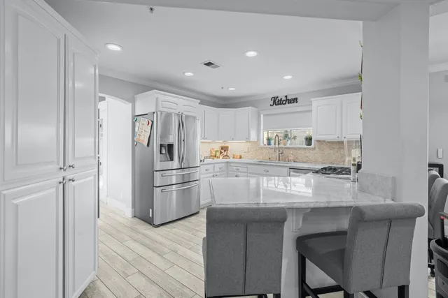 a kitchen with kitchen island granite countertop a refrigerator and wooden cabinets