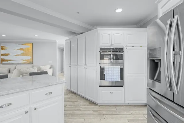 a view of kitchen with stainless steel appliances granite countertop white cabinets and refrigerator