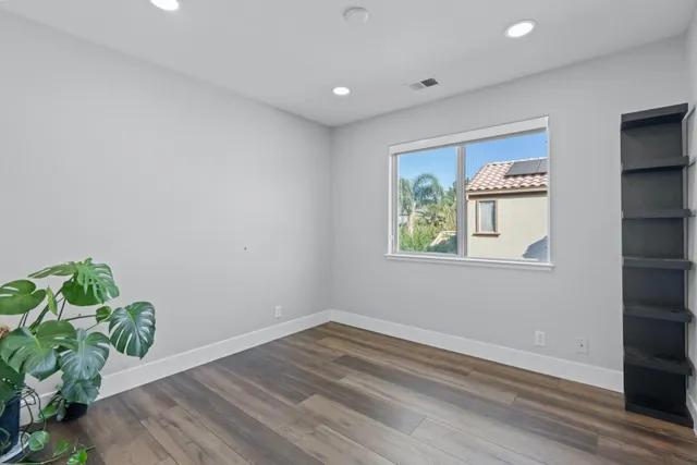 a view of empty room with wooden floor and window
