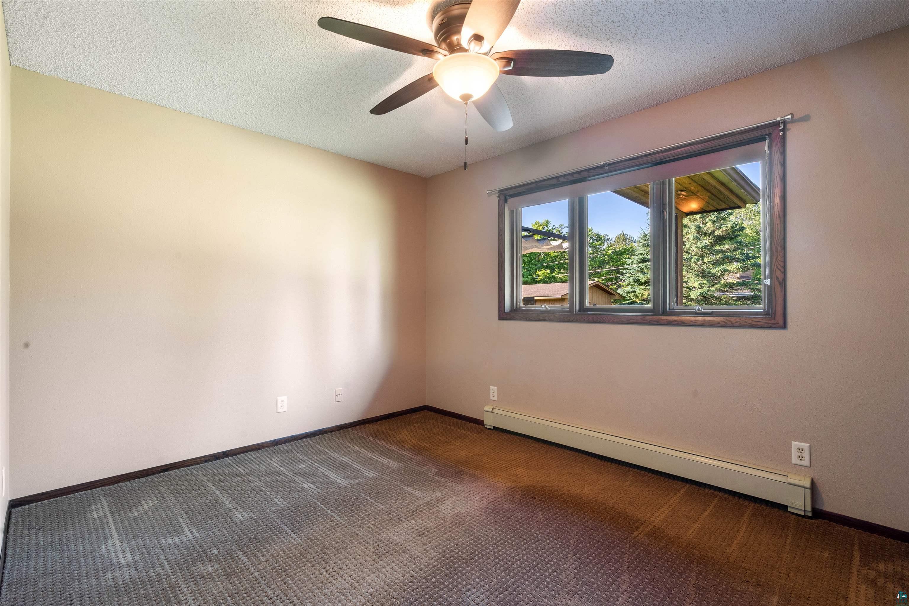44 Highgate Street Superior, WI 54880 - Photo 20 of 47 Bedroom featuring a multi-pane window with dark wood trim, overhead ceiling fan with integrated lighting, and baseboard heating