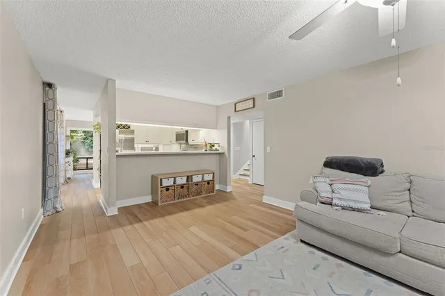 a view of a livingroom with wooden floor and kitchen view