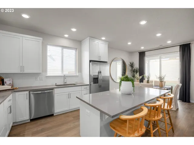 a kitchen with stainless steel appliances kitchen island granite countertop a dining table chairs and white cabinets