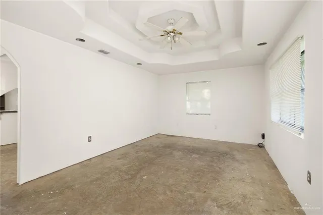 an empty room with a chandelier fan and windows