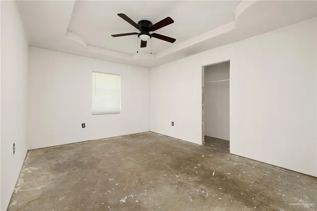 an empty room with ceiling fan and window