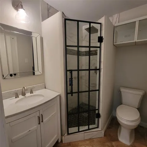 a bathroom with a shower sink vanity and toilet