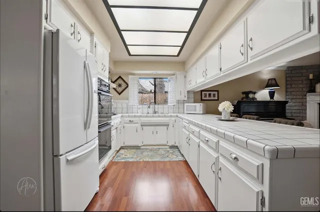 a kitchen with stainless steel appliances a refrigerator a sink and white cabinets