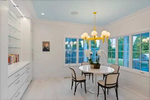 a dining room with furniture large windows and a chandelier